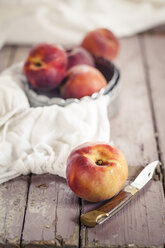 Bowl of peaches, knife and cloth on wood - SBDF001120