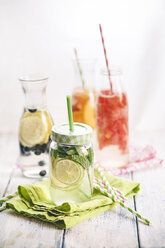 Carafes of miscellaneous fruit infused water on cloth and wood - SBDF001124