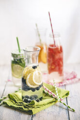 Carafes of miscellaneous fruit infused water on cloth and wood - SBDF001125