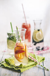 Carafes of miscellaneous fruit infused water on cloth and wood - SBDF001127