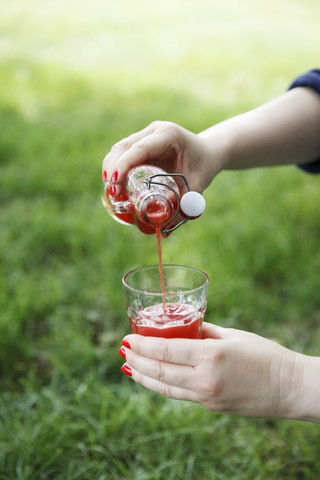 Frau gießt Erdbeersirup in ein Glas, lizenzfreies Stockfoto