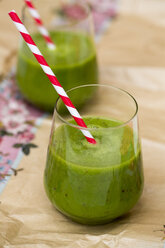 Two glasses of green smoothie with drinking straws on packing paper - SARF000748