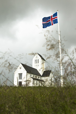 Iceland, view to church of Skalholt with blowing national flag on flaspole in the foreground stock photo