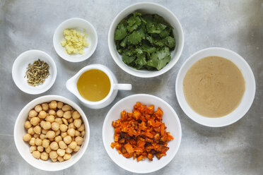 Bowls of ingredients of carrot fennel hummus on metal, elevated view - EVG000742