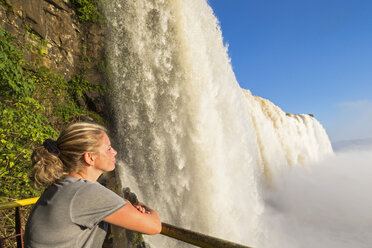 Brazil, Parana, Iguazu National Park, woman standing on view terrace in front of waterfall - FOF006685