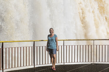 Brazil, Parana, Iguazu National Park, female tourist standing in front of waterfall - FOF006694