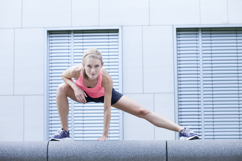 Young woman doing stretching exercise in front of facade of an office building stock photo