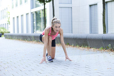 Young woman in start position in front of an office building - MAEF008887