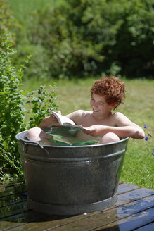 Junge badet in einer Zinkwanne und liest ein Buch - LBF000886