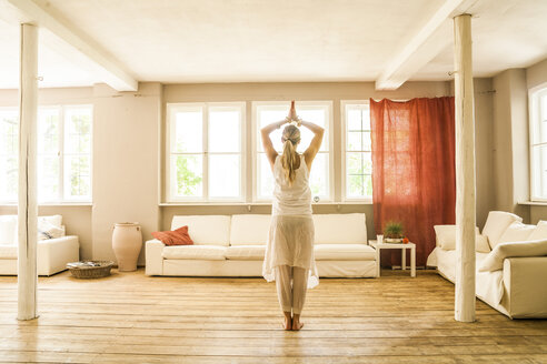 Woman practicing yoga in living room - TCF004154