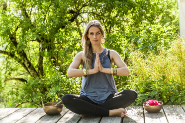 Frau übt Yoga auf einer Holzterrasse - TCF004213