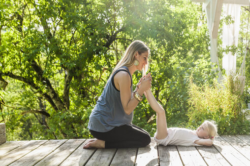 Mutter und Tochter üben Yoga auf einer Holzterrasse - TCF004216