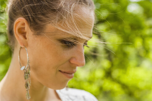 Smiling woman with earring outdoors - TCF004174