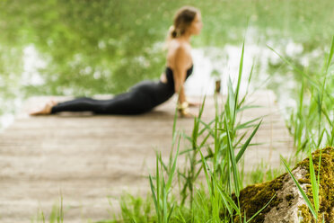 Frau übt Yoga auf dem Bootssteg - TCF004180