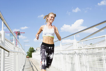 Germany, Munich, Female jogger running on a bridge - MAEF008903