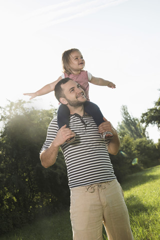 Father carrying little daughter on shoulders stock photo