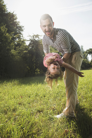 Vater spielt mit seiner kleinen Tochter auf einer Wiese, lizenzfreies Stockfoto