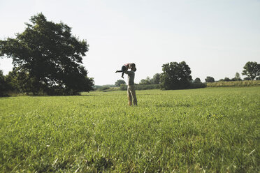 Father scooping his little daughter up in the air on a meadow - UUF001523