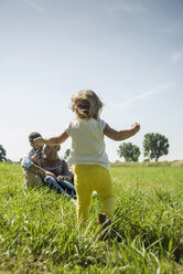 Parents and little daughter relaxing on a meadow - UUF001532