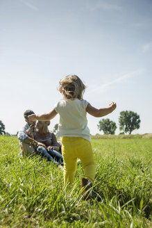 Eltern und kleine Tochter entspannen sich auf einer Wiese - UUF001532