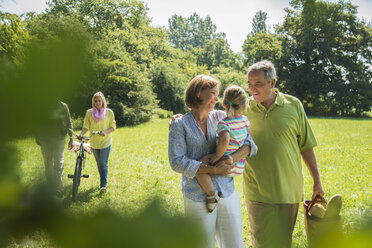 Drei Generationen Familie beim Spaziergang auf einer Wiese - UUF001536