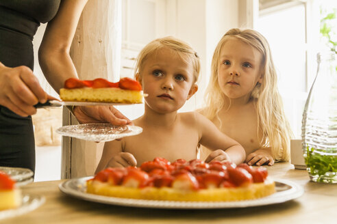 Woman dividing strawberry cake for two girls - TCF004207