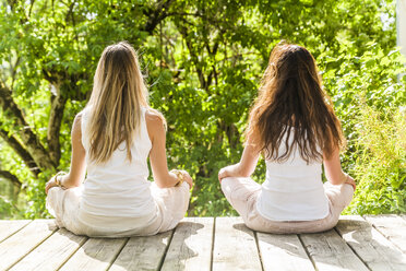 Zwei Frauen praktizieren Yoga im Freien - TCF004204