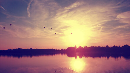 Germany, North Rhine-Westphalia, Minden, balloons over lake at sunset - HOHF000920
