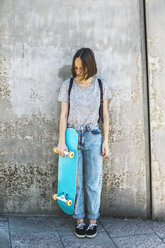 Spanien, Barcelona, junge Skateboarderin vor einer Wand stehend - EBSF000269