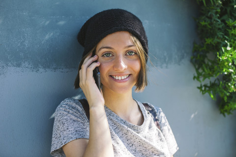 Porträt einer lächelnden jungen Skateboarderin, die mit einem Smartphone telefoniert, lizenzfreies Stockfoto