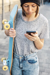 Porträt einer jungen Skateboarderin mit Smartphone - EBSF000289