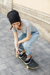 Smiling young female skate boarder on her skateboard - EBSF000294