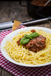 Teller mit Spaghetti Bolognese, dekoriert mit Basilikumblättern auf Stoff und dunklem Holz - LVF001737