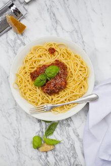 Teller mit Spaghetti Bolognese, Tuch, Parmesan und Basilikumblättern auf weißem Marmor, Ansicht von oben - LVF001738