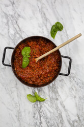 Kochtopf mit Bolognesesauce und Basilikumblättern auf weißem Marmor, Ansicht von oben - LVF001740