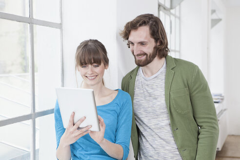 Two colleagues looking at digital tablet in a creative office - RBF001786