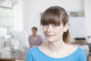 Porträt einer lächelnden jungen Frau in einem kreativen Büro - RBF001728