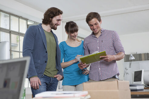 Three colleagues looking at notes in a creative office - RBF001746