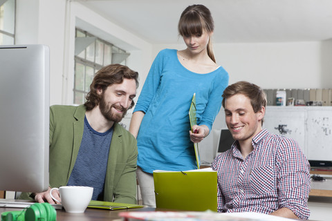 Drei Kollegen arbeiten zusammen in einem kreativen Büro, lizenzfreies Stockfoto