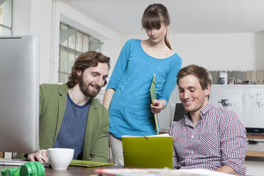 Drei Kollegen arbeiten zusammen in einem kreativen Büro - RBF001756