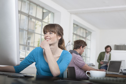 Portrait of young woman working at computer in a creative office stock photo