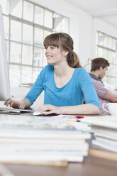 Portrait of young woman working at computer in a creative office - RBF001769