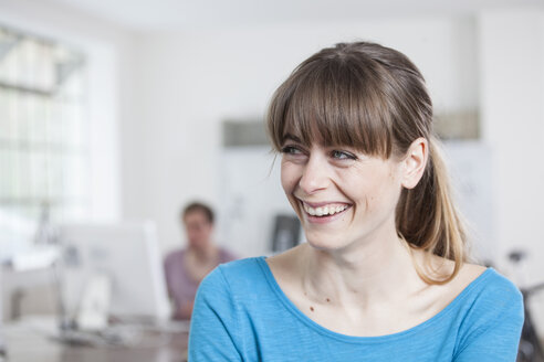 Portrait of laughing young woman in an creative office - RBF001781