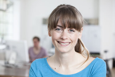 Porträt einer lächelnden jungen Frau in einem kreativen Büro - RBF001782