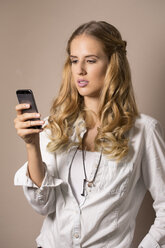 Porträt einer jungen Frau, die eine SMS liest - FCF000394