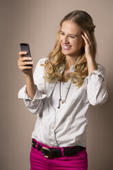 Porträt einer lächelnden jungen Frau, die auf ihr Smartphone schaut - FCF000395