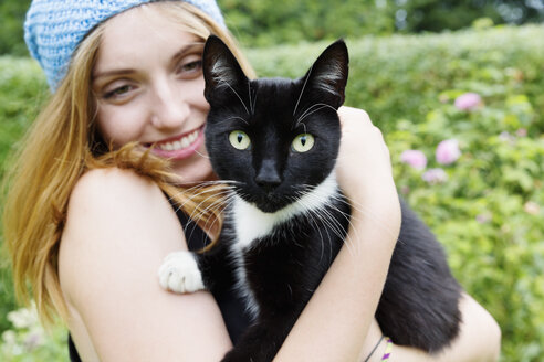 Porträt einer lächelnden jungen Frau, die eine Katze auf dem Arm hält - SEF000831