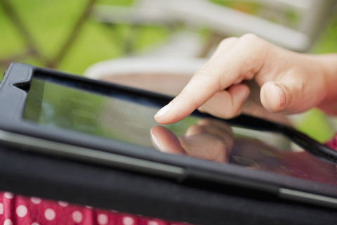 Finger einer jungen Frau berührt das Display eines digitalen Tablets, Nahaufnahme, lizenzfreies Stockfoto