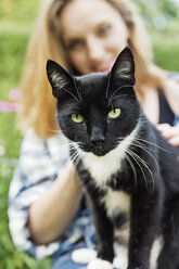 Porträt einer Katze mit lächelnder junger Frau im Hintergrund - SEF000837