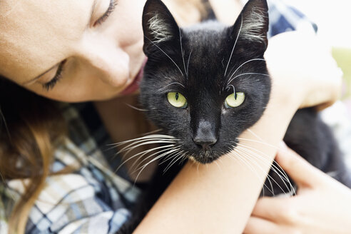 Junge Frau hält schwarze Katze auf ihren Armen, Teilansicht - SEF000838